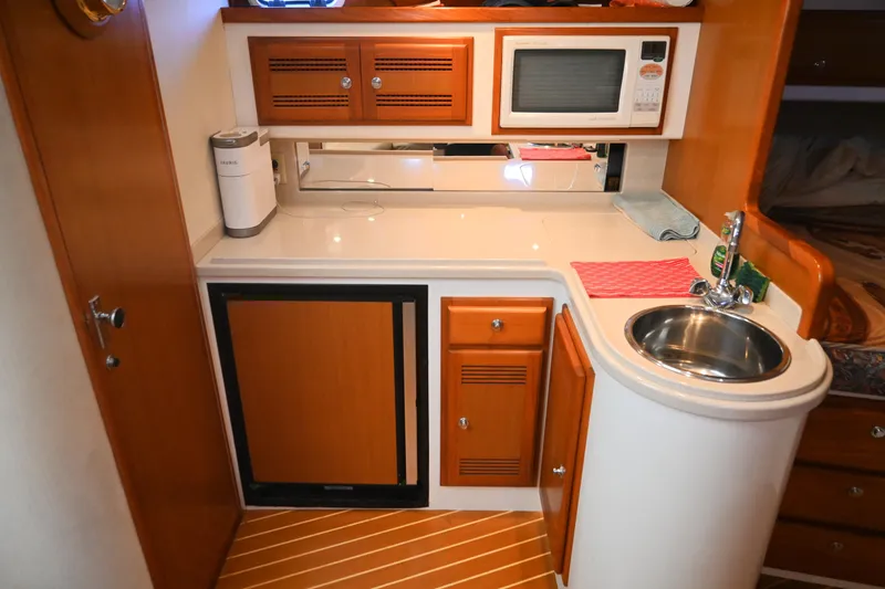 Slide: The Image of 2001 Cabo 35 Express yacht kitchenette with sink, microwave, and wooden cabinetry. - 44