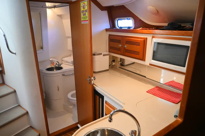 Slide: The Image of 2001 Cabo 35 Express interior with kitchenette, sink, microwave, and bathroom. - 47