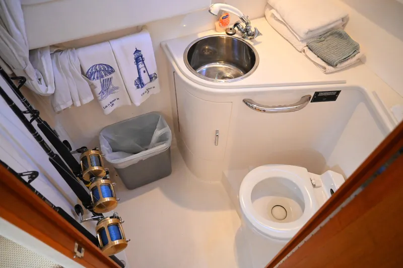Slide: The Image of 2001 Cabo 35 Express boat bathroom with sink, toilet, and fishing rods. - 48