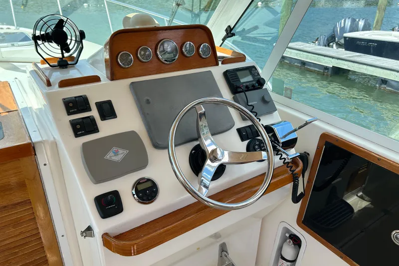 Slide: The Image of 2005 Hunt Yachts Surfhunter 33 cockpit with blue seating and helm, docked by the water. - 6