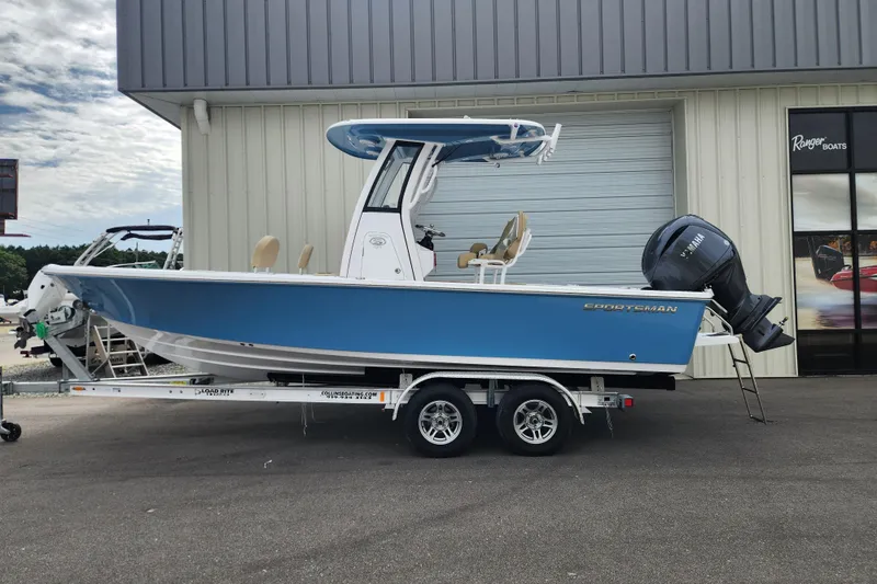 Slide: The Image of 2026 Sportsman Masters 227 Bay Boat in blue on trailer, parked outside a building. - 0