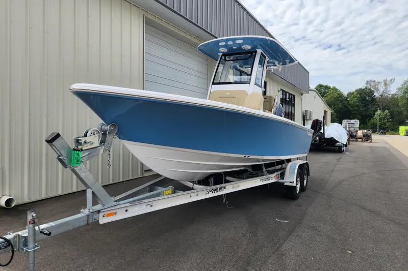 Slide: The Image of 2026 Sportsman Masters 227 Bay Boat on trailer, parked outside a warehouse. - 1