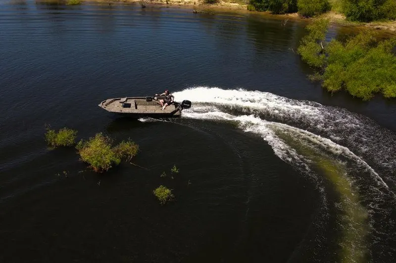 Slide: The Image of 2026 SeaArk 1752 Slayer X boat navigating through water with lush greenery. - 26