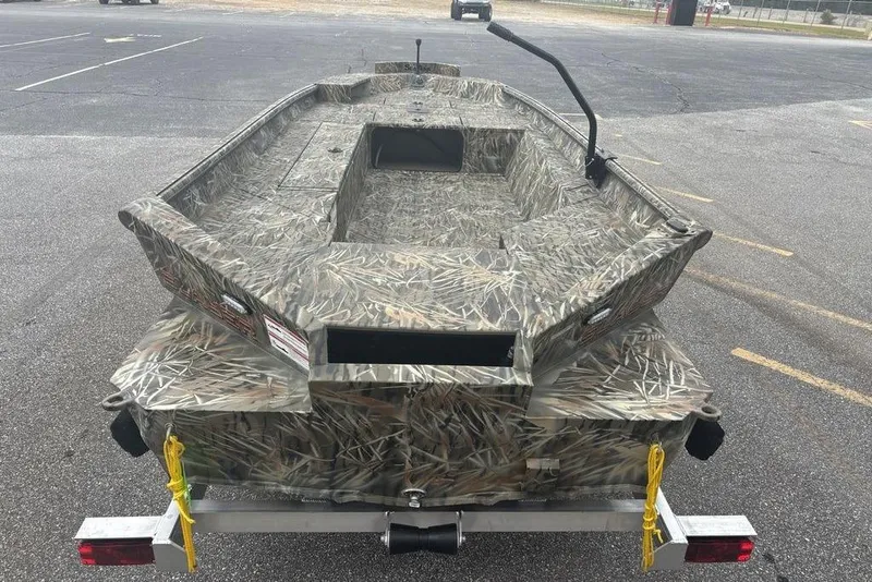 The Image of 2026 SeaArk 1752 Slayer X boat with camouflage design on a trailer outside a building. - 3