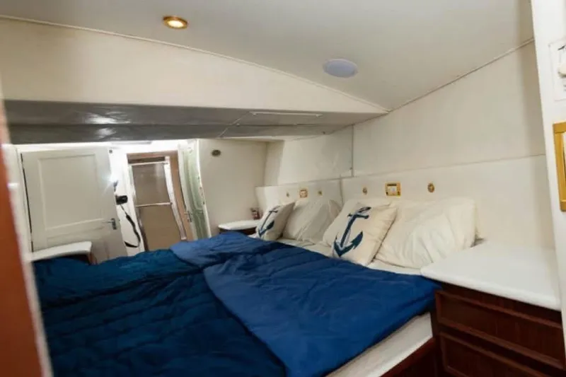 Slide: The Image of Interior cabin of 1979 Hatteras Sportfish 53' yacht with nautical-themed bedding. - 53