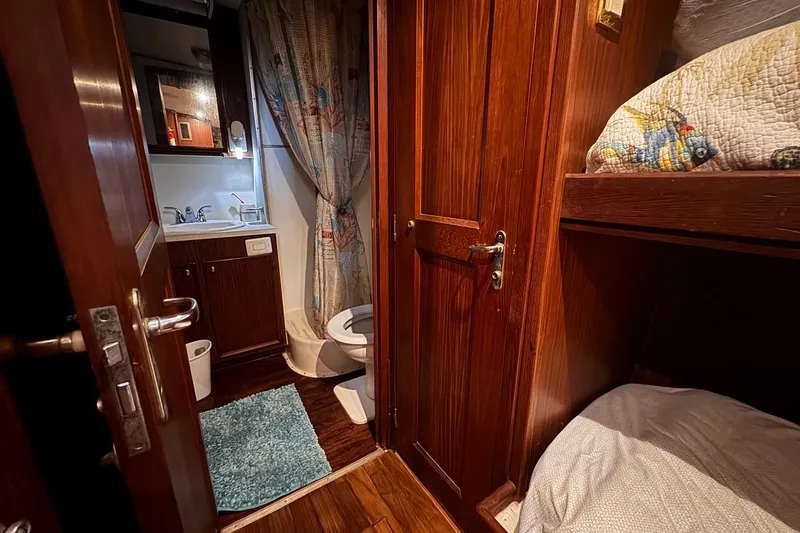 Slide: The Image of 1979 Hatteras 53 Motor Yacht interior with wooden cabinetry, bathroom, and cozy sleeping area. - 58