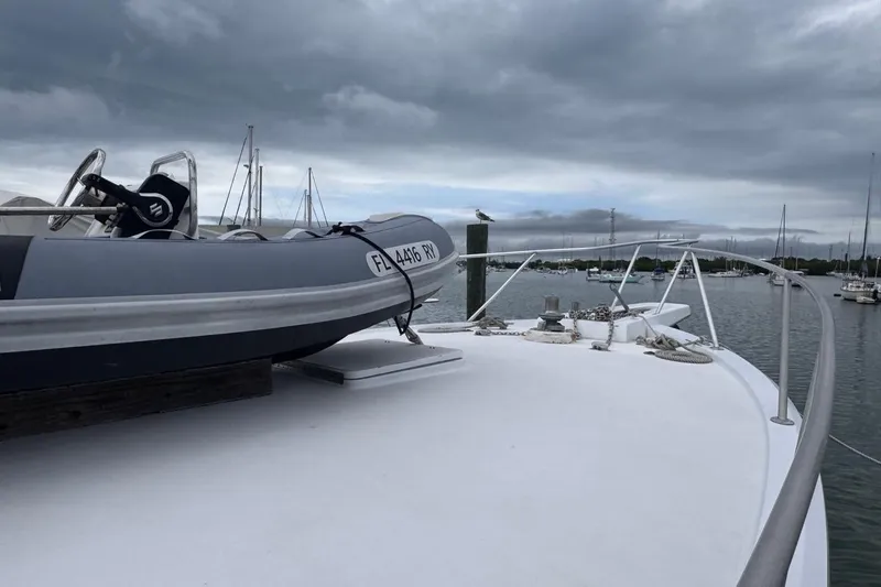 Slide: The Image of 1979 Hatteras 53 Motor Yacht deck with dinghy, moored in a marina under cloudy skies. - 66