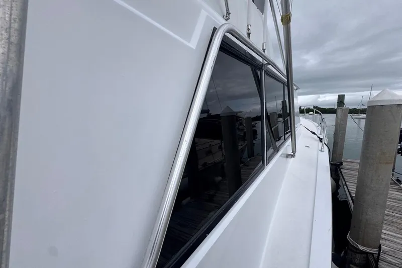 Slide: The Image of 1979 Hatteras 53 Motor Yacht docked, showcasing sleek side view and windows. - 68