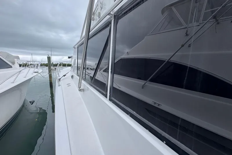 Slide: The Image of 1979 Hatteras 53 Motor Yacht docked, reflecting nearby boats under cloudy skies. - 79