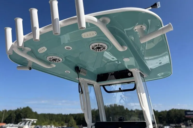 Slide: The Image of 2026 Sportsman Heritage 231 boat with rod holders and speakers under a clear blue sky. - 16