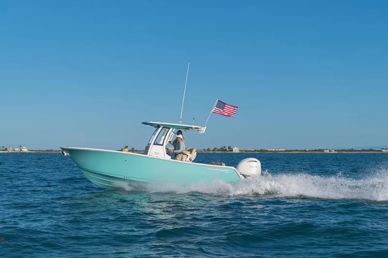 Slide: The Image of 2026 Sportsman Heritage 231 boat cruising on open water with American flag. - 27