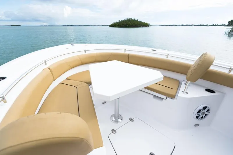 Slide: The Image of 2026 Sportsman Heritage 231 boat interior with tan seating and white table on calm water. - 46