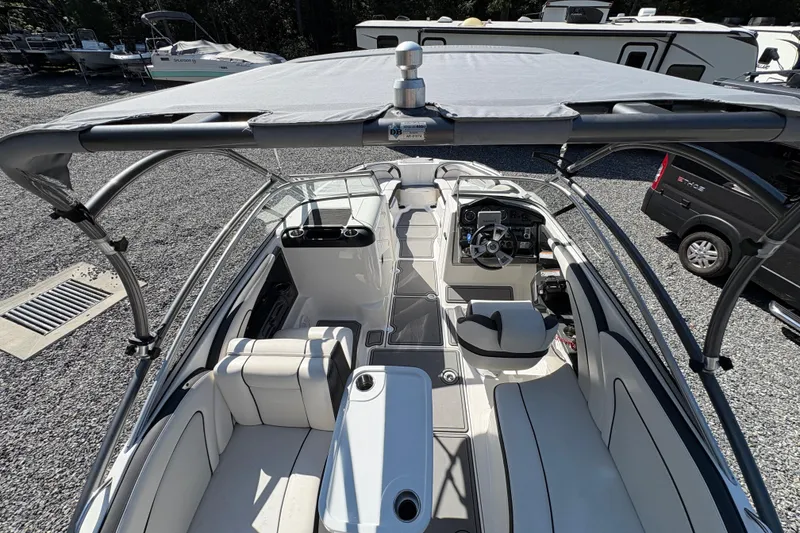 Slide: The Image of 2013 Yamaha Boats AR240 HO interior with seating, steering console, and canopy in a parking area. - 22