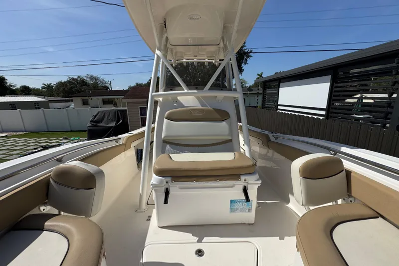 Slide: The Image of 2020 Pioneer 222 Islander boat interior with seating and cooler, parked outdoors. - 18