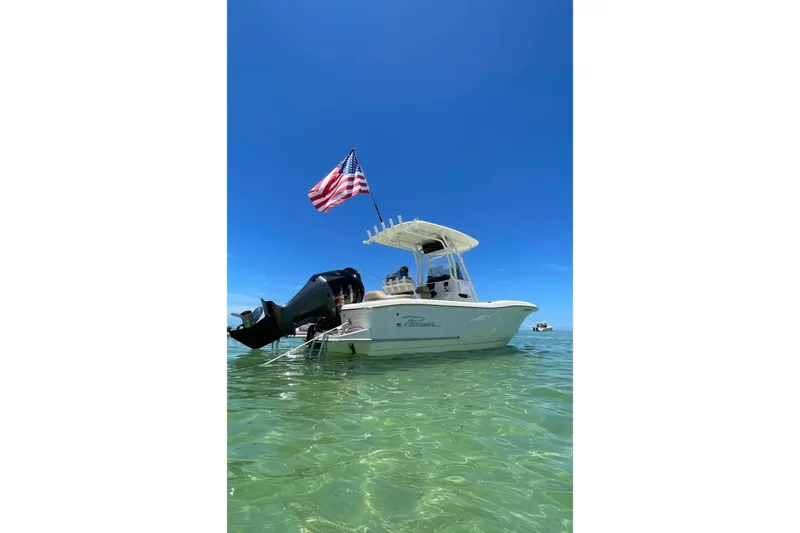 Slide: The Image of 2020 Pioneer 222 Islander boat with American flag on clear water. - 2