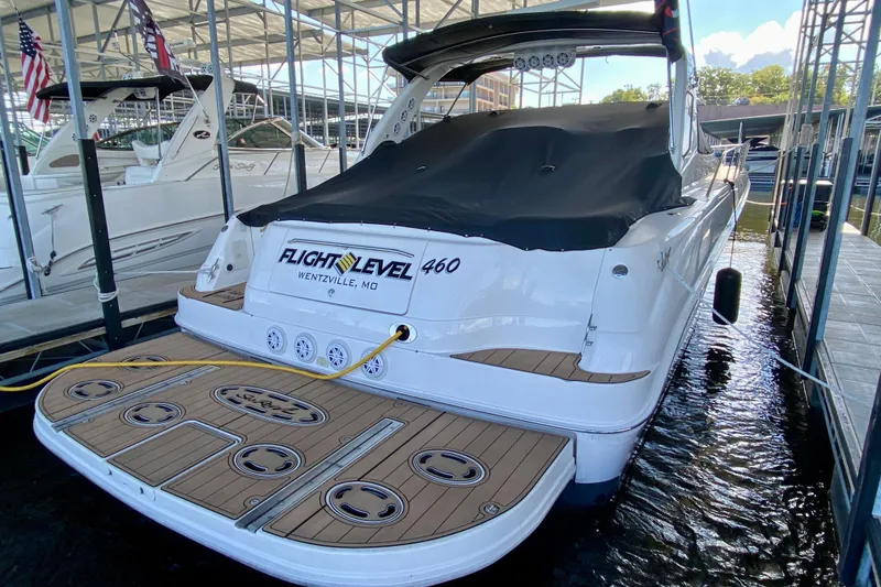Slide: The Image of 1999 Sea Ray 460 Sundancer docked, rear view with covered deck and branding. - 1