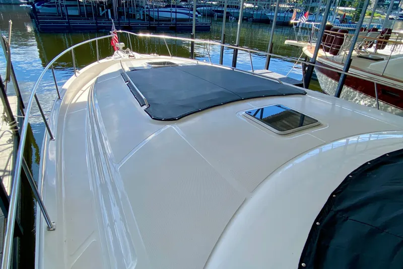 Slide: The Image of 1999 Sea Ray 460 Sundancer yacht docked, showcasing sleek deck design and covered hatch. - 5