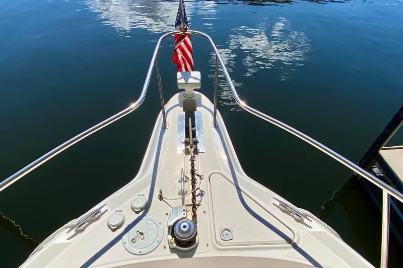 Slide: The Image of Bow view of 1999 Sea Ray 460 Sundancer yacht with American flag on calm water. - 7