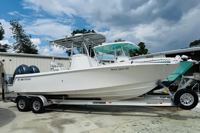 Slide: The Image of 2024 Contender 25 Open boat on trailer, parked outdoors under cloudy sky. - 11