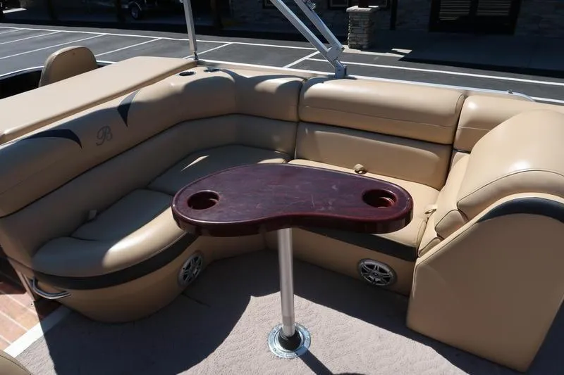 Slide: The Image of 2013 Berkshire 231RFCSTS13 pontoon boat interior with beige seating and a wooden table. - 10