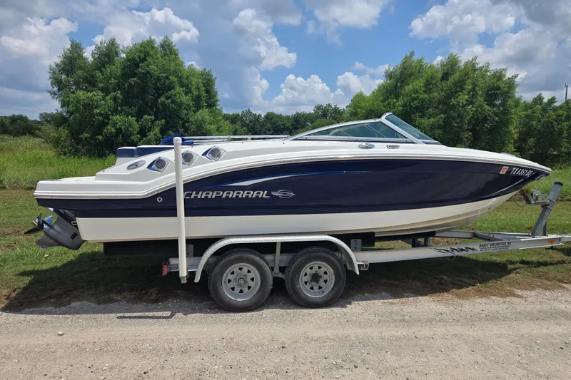 Slide: The Image of 2010 Chaparral 206 SSi boat on trailer, parked outdoors with lush greenery background. - 3