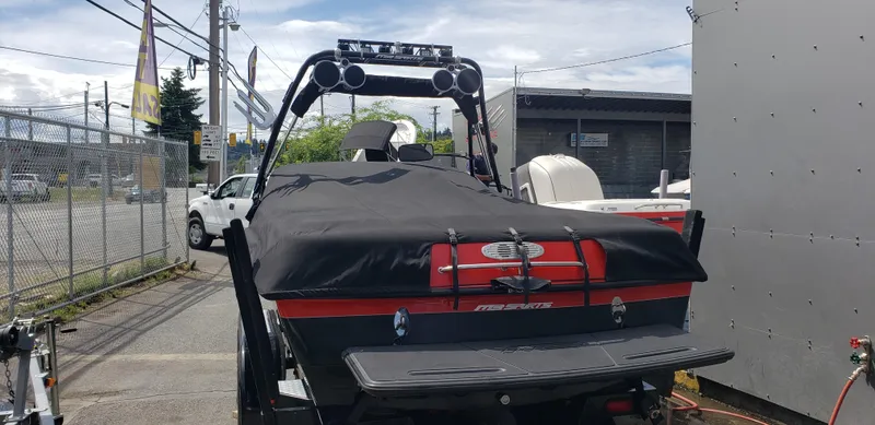 Slide: The Image of 2004 MB B52-21 V/SK boat with cover, parked outdoors near a fence and building. - 2