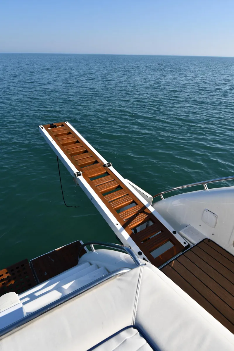 Slide: The Image of Sunseeker 55 CAMARGUE 1996 yacht with wooden gangway over calm sea. - 34