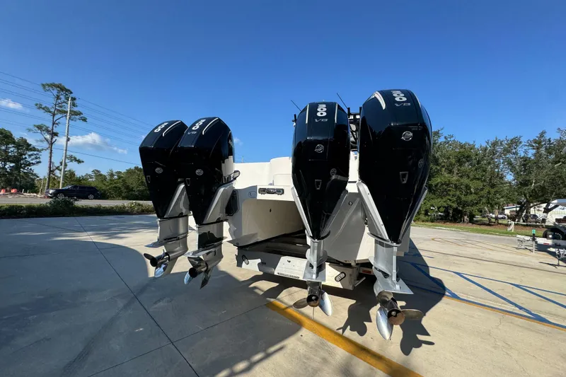 Slide: The Image of 2023 Invincible 35 Catamaran with triple outboard engines, parked outdoors under clear blue sky. - 14