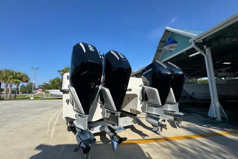 Slide: The Image of 2023 Invincible 35 Catamaran with triple outboard engines, parked outdoors under clear blue sky. - 16