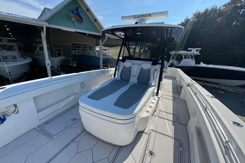 Slide: The Image of 2023 Invincible 35 Catamaran with cushioned seating, docked near a boat dealership. - 20