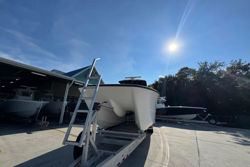 Slide: The Image of 2023 Invincible 35 Catamaran on trailer under bright sun, near storage facility. - 5