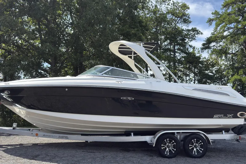Slide: The Image of 2007 Sea Ray 250 SLX boat on trailer, surrounded by trees, under clear sky. - 15