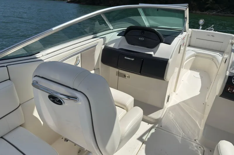 Slide: The Image of 2007 Sea Ray 250 SLX boat interior with white seating and dashboard, on a sunny day. - 6