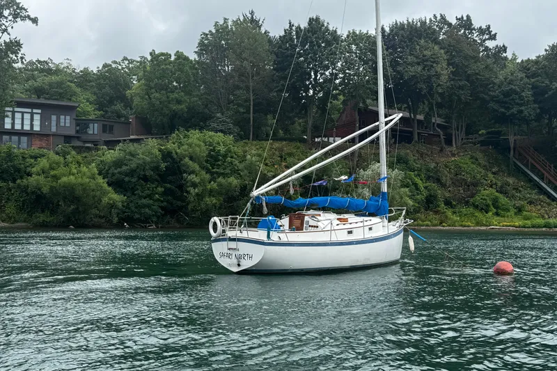 Slide: The Image of 1984 Nonsuch 26 Classic sailboat anchored near lush shoreline. - 2