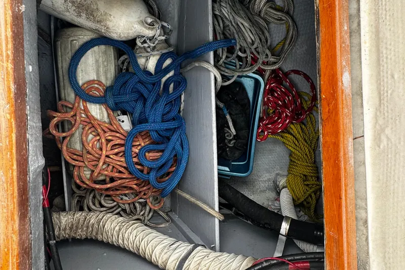 Slide: The Image of Storage compartment on a 1984 Nonsuch 26 Classic boat with various ropes and equipment. - 34