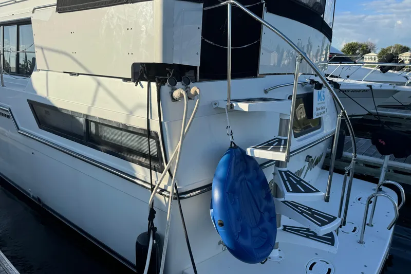 Slide: The Image of 1990 Carver 3807 Aft Cabin yacht docked, featuring exterior stairs and blue fender. - 15