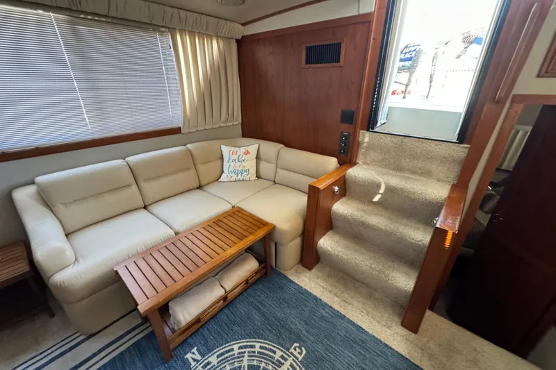 Slide: The Image of 1990 Carver 3807 Aft Cabin interior with beige sofa, wooden table, and carpeted stairs. - 35