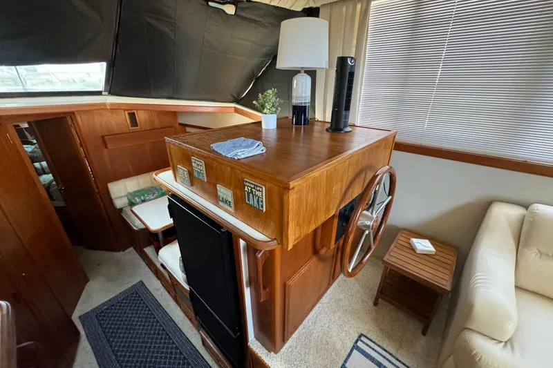 Slide: The Image of 1990 Carver 3807 Aft Cabin interior with wooden helm, seating, and decor accents. - 38