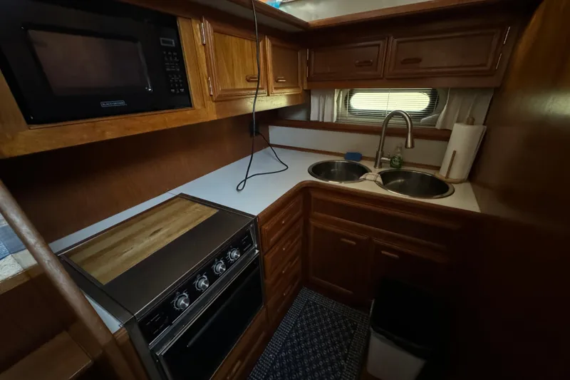 Slide: The Image of 1990 Carver 3807 Aft Cabin kitchen with stove, microwave, and dual sink. - 40