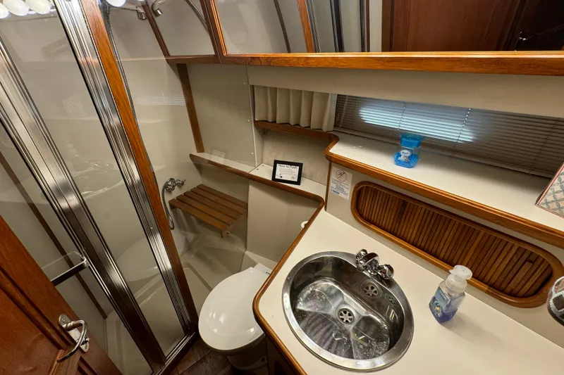 Slide: The Image of 1990 Carver 3807 Aft Cabin bathroom with shower, sink, and wooden accents. - 43