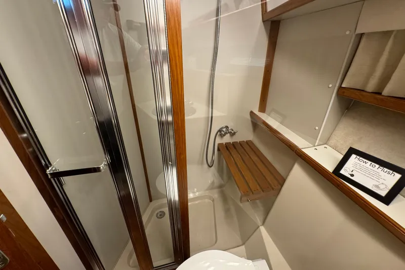 Slide: The Image of 1990 Carver 3807 Aft Cabin bathroom with shower, wooden accents, and flush instructions. - 44
