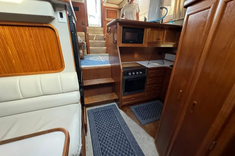 Slide: The Image of 1990 Carver 3807 Aft Cabin interior with wood cabinetry, kitchen appliances, and carpeted stairs. - 47