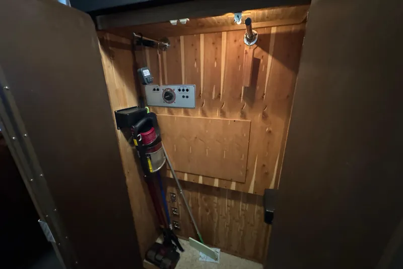 Slide: The Image of 1990 Carver 3807 Aft Cabin interior with wooden paneling and cleaning equipment. - 57