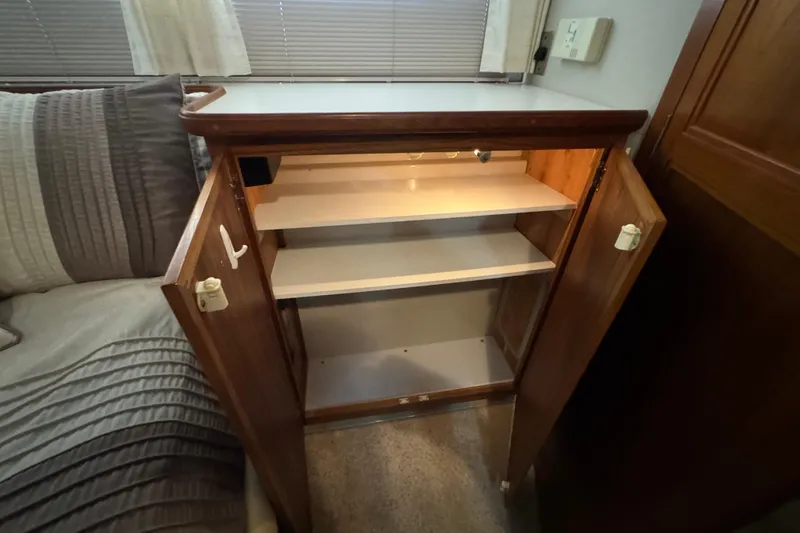 Slide: The Image of Open wooden cabinet with shelves inside a 1990 Carver 3807 Aft Cabin boat interior. - 58