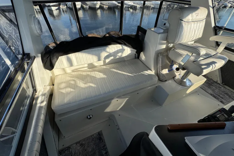 Slide: The Image of 1990 Carver 3807 Aft Cabin interior with white seating and marina view. - 70