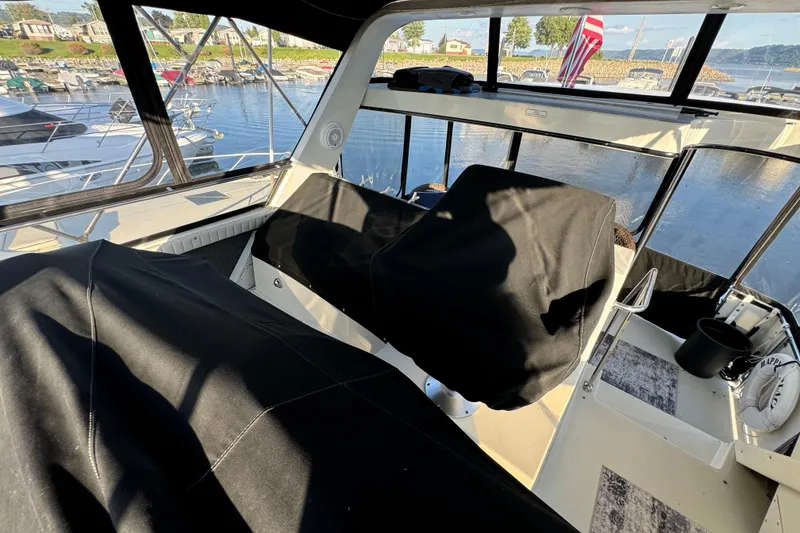 Slide: The Image of 1990 Carver 3807 Aft Cabin interior with covered seats and marina view. - 77