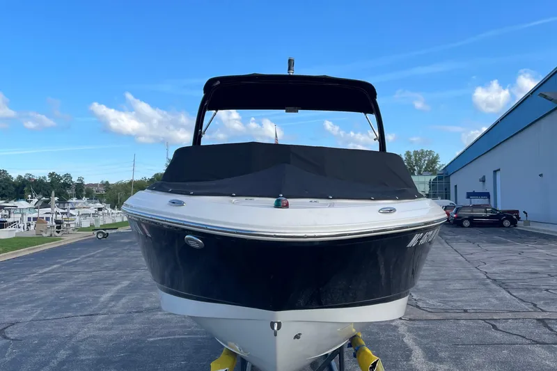 Slide: The Image of 2019 Chaparral 21 H2O Sport boat on display, black hull, covered, clear sky background. - 2
