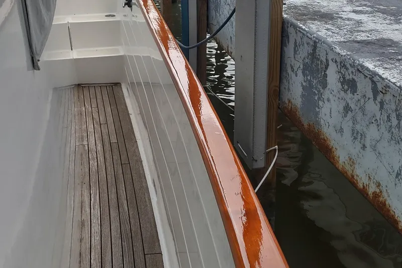 Slide: The Image of Kadey-Krogen 39 yacht deck with polished wood railing, docked beside a weathered pier. - 15