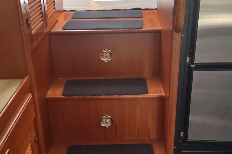 Slide: The Image of Wooden stairs with black mats inside a 2001 Kadey-Krogen 39 boat interior. - 40