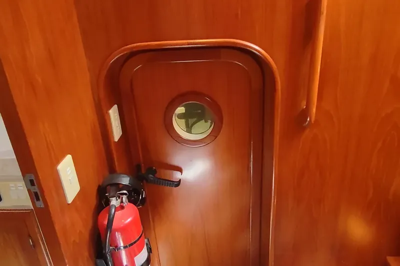 Slide: The Image of Wooden interior door with porthole and fire extinguisher on a 2001 Kadey-Krogen 39 boat. - 69